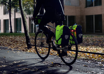 Éclairage et sacoches réfléchissantes contribuent à la visibilité du ou de la cycliste.